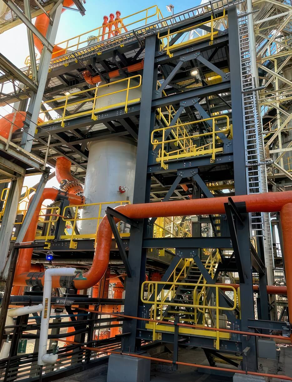 Large-diameter FRP piping with flanged joints and 90-degree elbows on a steel support structure at an industrial process plant