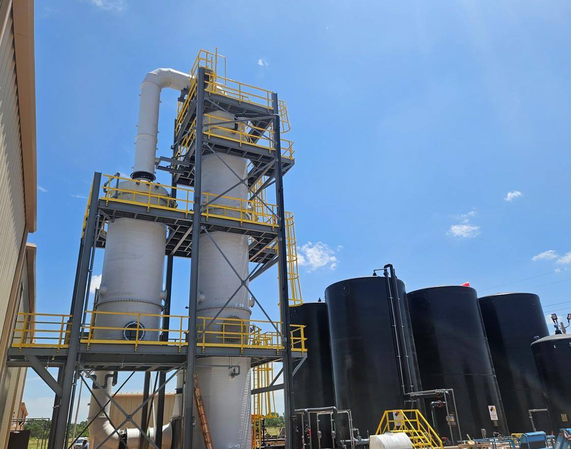 Torre lavadora de gases y ductos de FRP montados sobre estructura de acero en una planta industrial